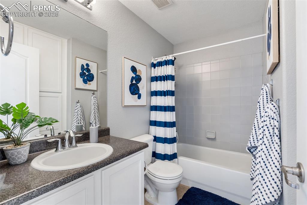 Image 31 of 50: Full bath featuring vanity, shower / tub combo, and a textured wall