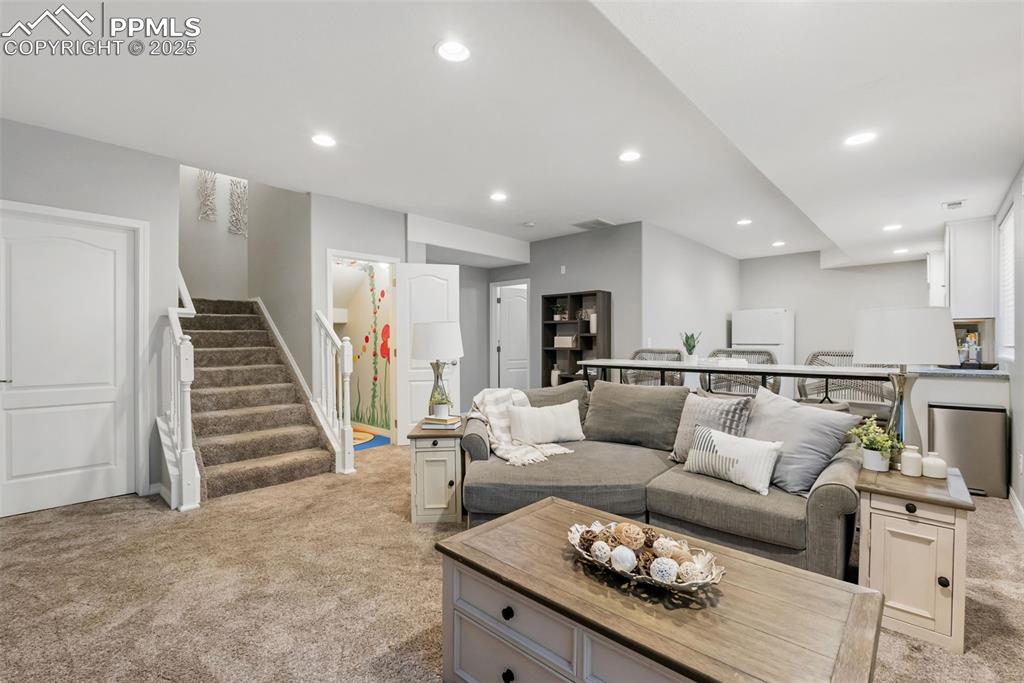 Image 33 of 50: Living room featuring stairs, light colored carpet, and recessed lighting