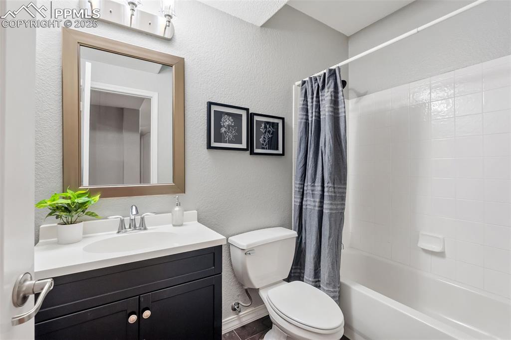 Image 38 of 50: Full bathroom featuring a textured wall, shower / bath combo with shower cu