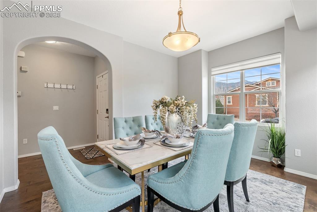 Image 5 of 50: Dining space featuring arched walkways and dark wood finished floors