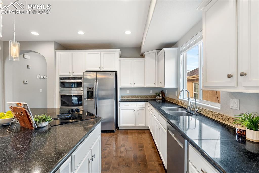 Image 9 of 50: Kitchen with white cabinetry, appliances with stainless steel finishes, dar