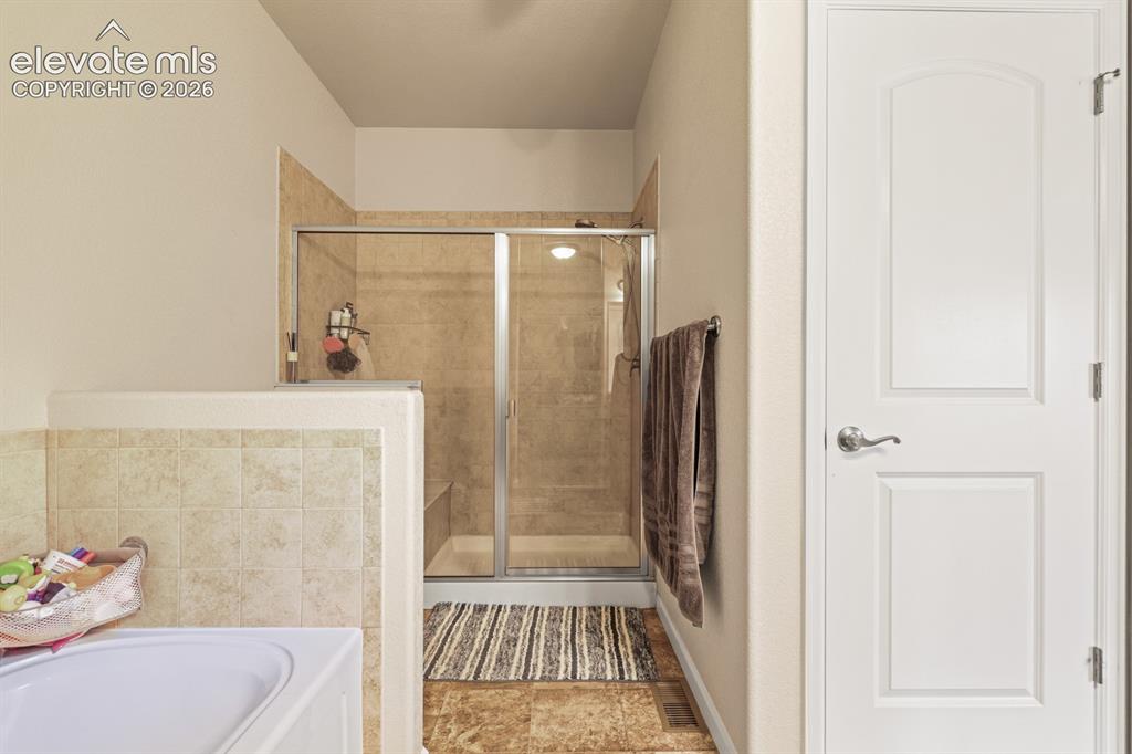 Image 17 of 38: The Main Level Primary Bathroom features a soaking tub and separate tiled s