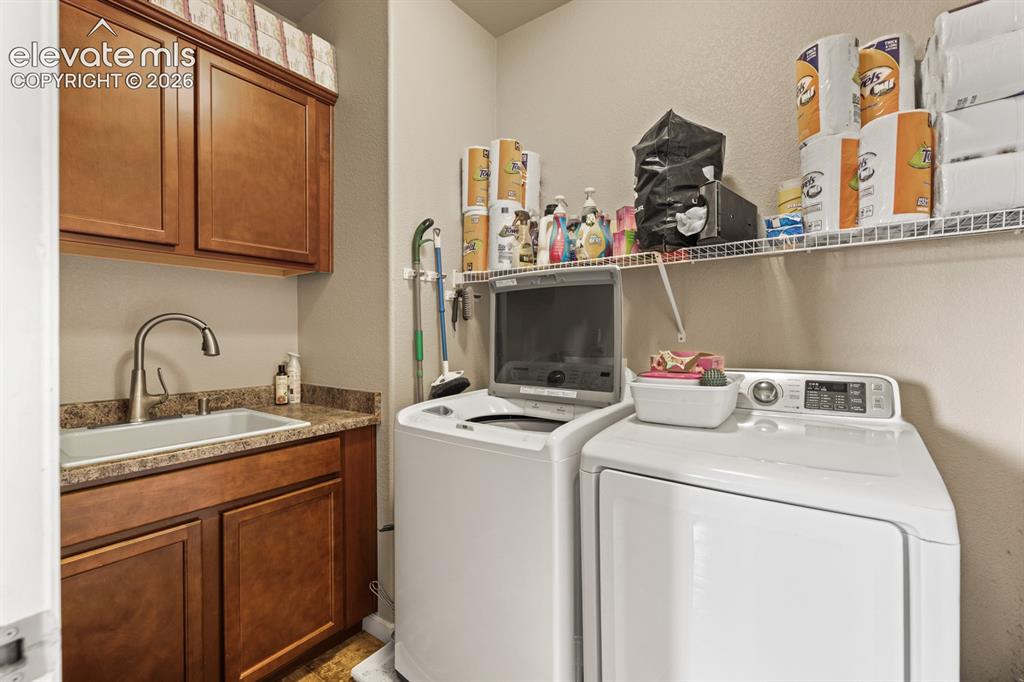 Image 20 of 38: The Laundry Room boasts a sink, cabinets, and washer and dryer that stay.