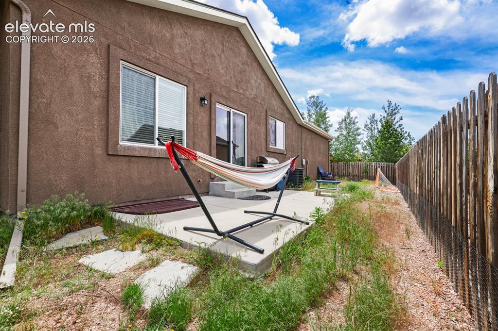 Image 33 of 38: Fenced backyard with concrete patio.