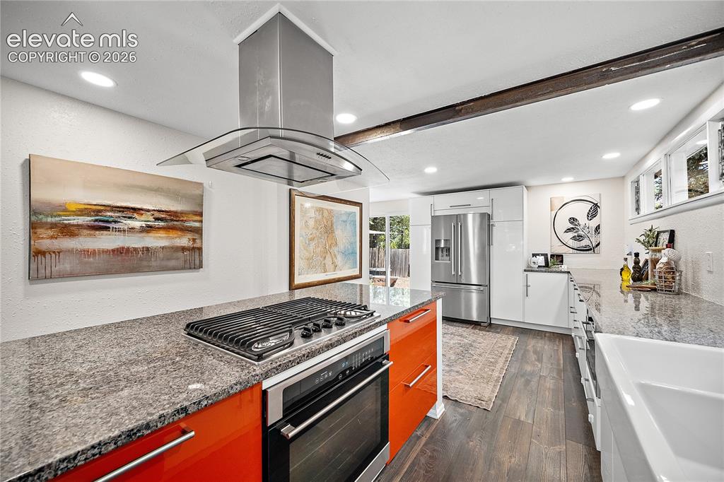 Image 14 of 41: Kitchen featuring an island with a built-in gas cooktop, stainless steel ra