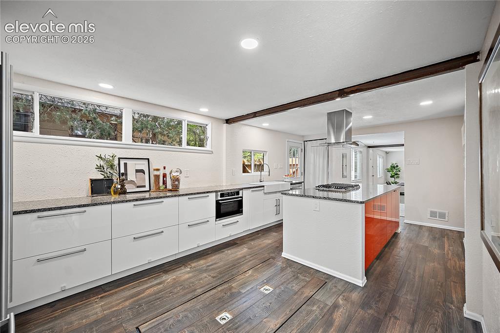 Image 17 of 41: Modern kitchen featuring dark wood-finish flooring, white flat-panel cabine