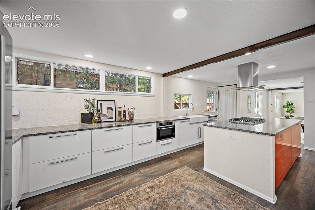 Image 18 of 41: Modern kitchen featuring white flat-panel cabinetry, granite countertops, a