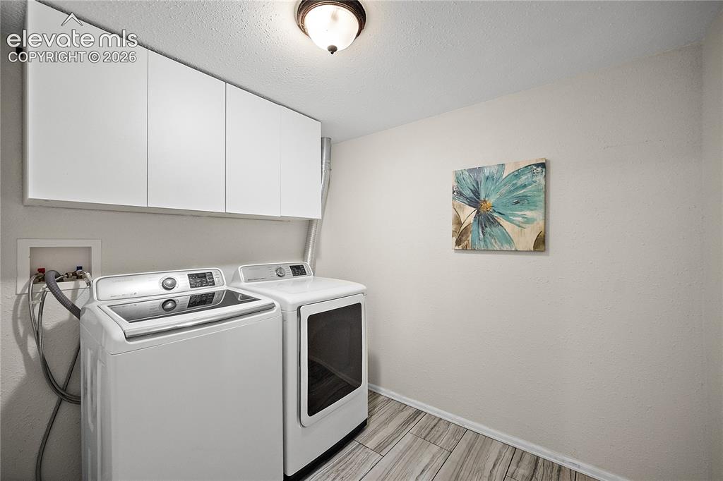 Image 30 of 41: Laundry area featuring white cabinetry, wood-finish flooring, a neutral wal