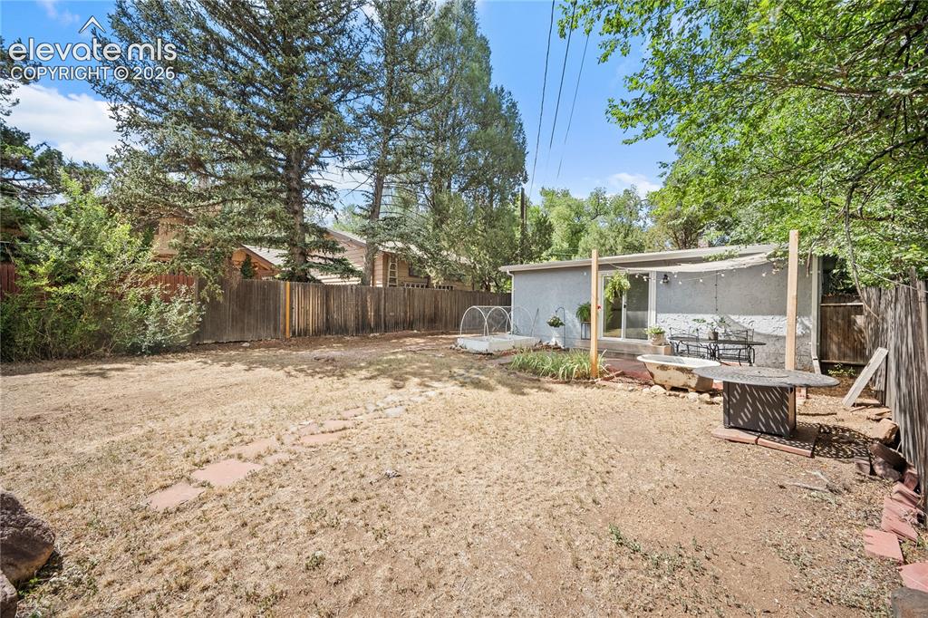 Image 34 of 41: Expansive yard area featuring a detached structure with large windows, a co
