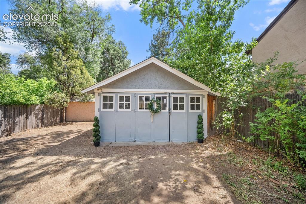 Image 36 of 41: Detached garage with a gray stucco finish and a gabled roofline