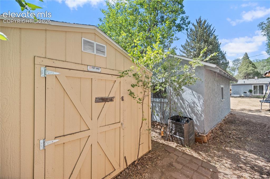 Image 37 of 41: Light-toned storage shed with double doors and upper vents