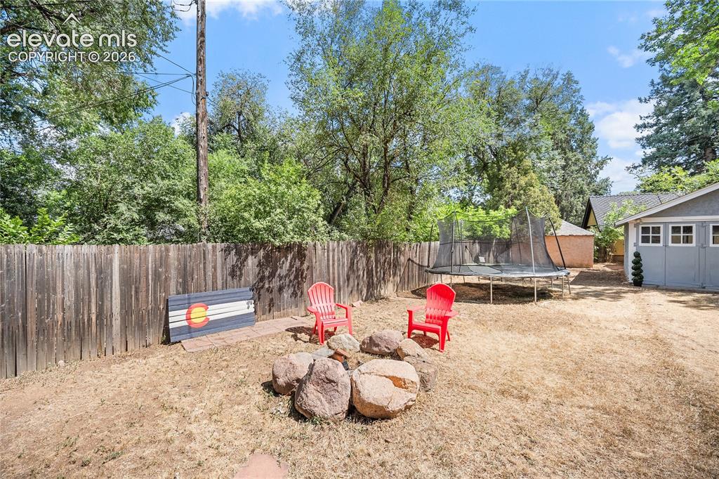 Image 40 of 41: Expansive backyard featuring a natural rock fire pit, wood privacy fencing,