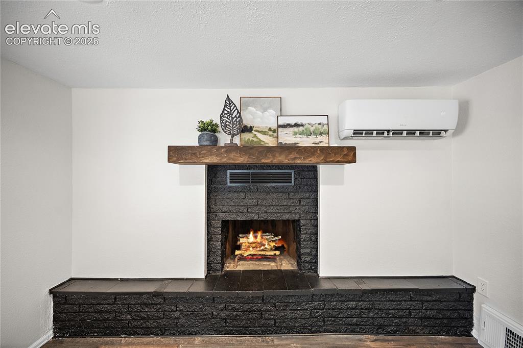 Image 8 of 41: Fireplace featuring a black brick surround, wood-finish mantel, and an elev
