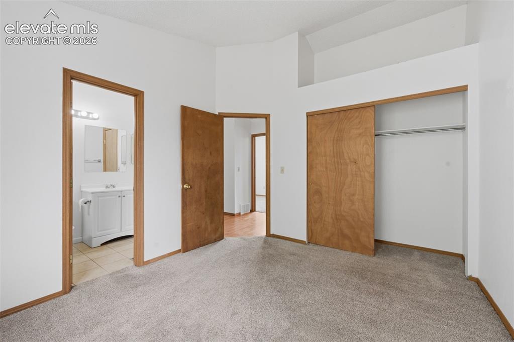 Image 10 of 29: Carpeted bedroom featuring a built-in closet with sliding wood doors, a vau