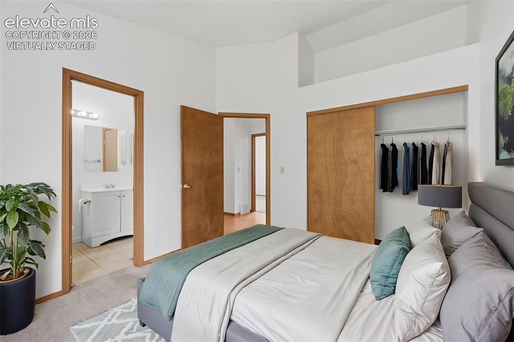 Image 11 of 29: Carpeted bedroom with a vaulted ceiling and wood-finish doors. Virtually St