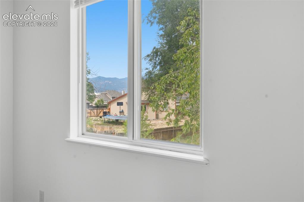 Image 12 of 29: Primary bedroom window with white trim, featuring a mountain backdrop and n