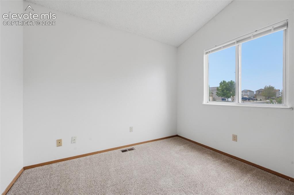 Image 14 of 29: Bright interior space featuring a large window, neutral carpeting, light-to