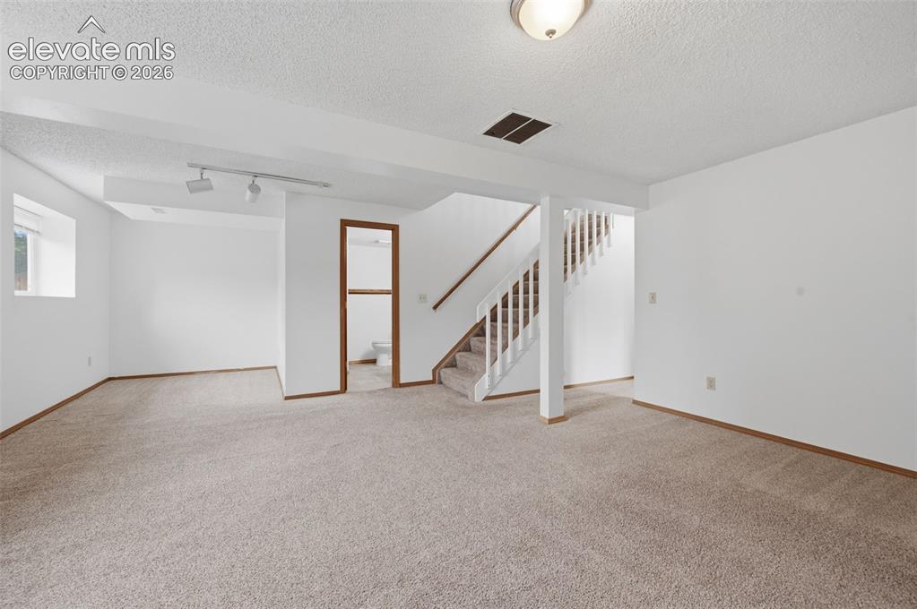 Image 20 of 29: Spacious family carpeted area featuring a staircase with wood handrails, a