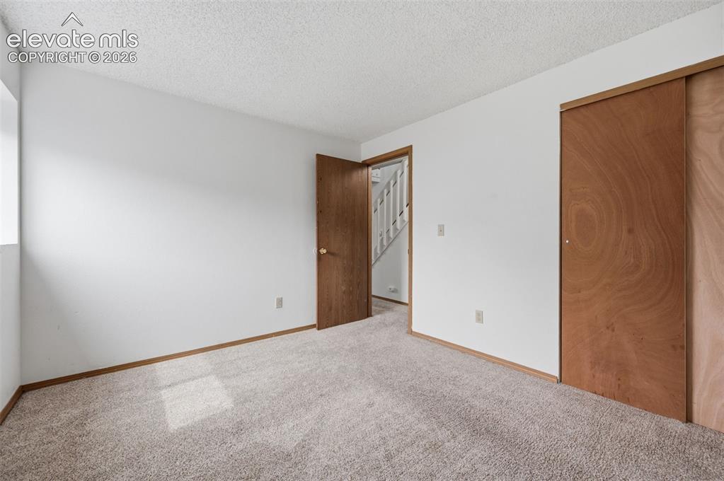 Image 24 of 29: Basement bedroom with closet view. Carpeted interior space with white walls