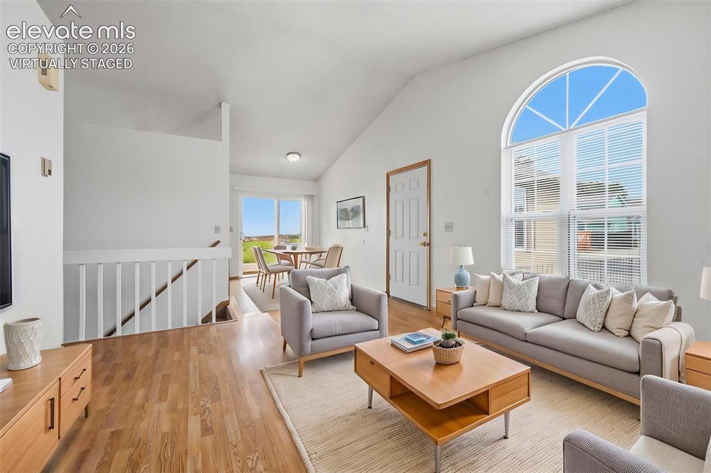 Image 5 of 29: Living area featuring a high vaulted ceiling, arched window, wood-finish fl