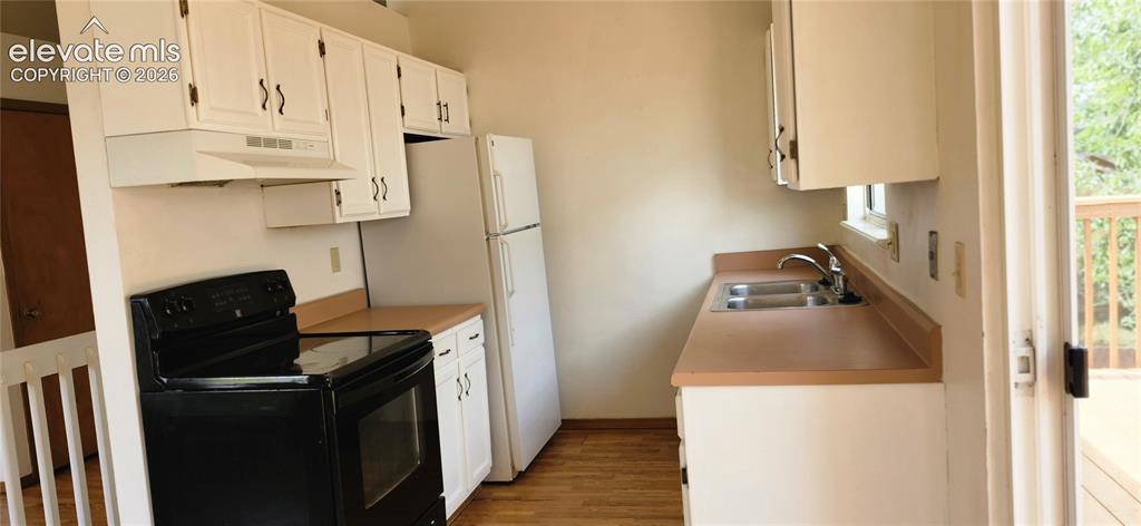 Image 7 of 29: Kitchen featuring white cabinetry, wood-finish flooring, and light-toned co