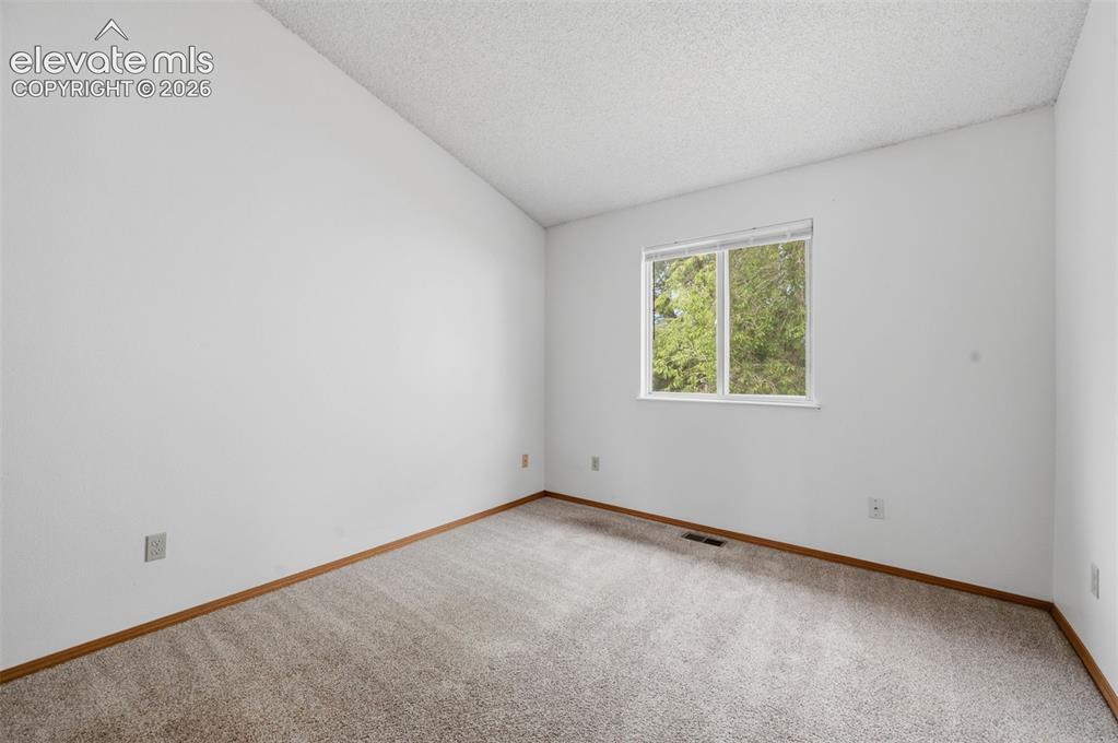 Image 8 of 29: Carpeted bedroom with white walls, wood-finish baseboards, and a double-pan