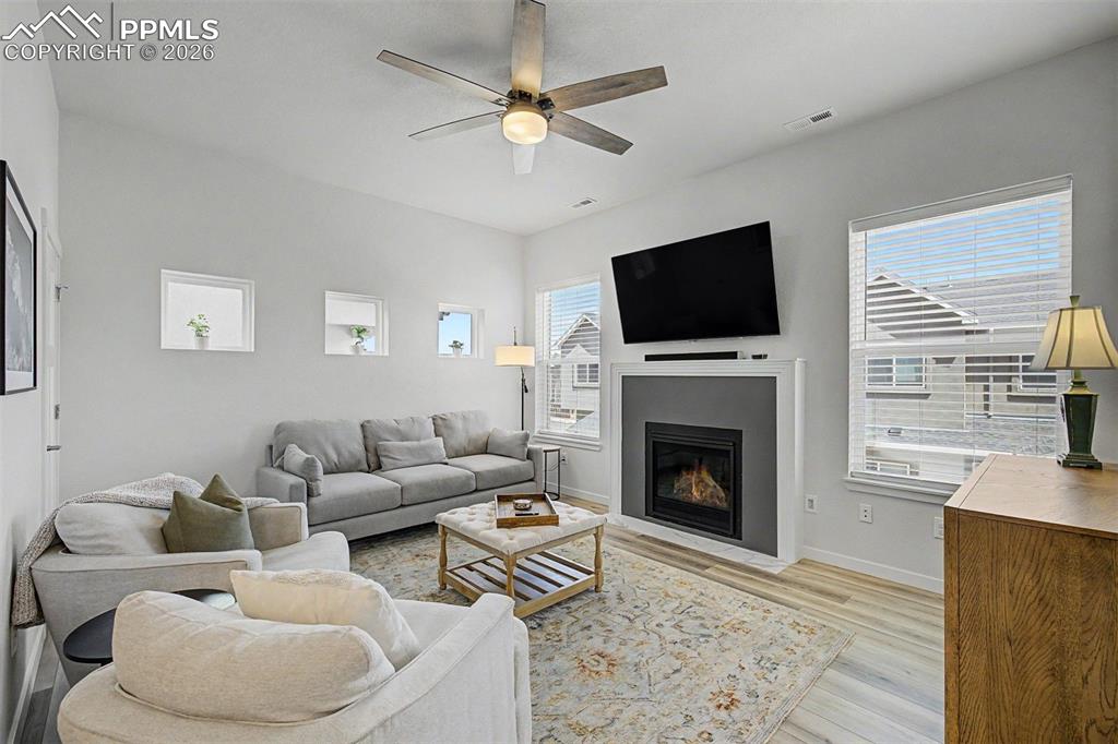 Image 12 of 39: The living room is the heart of the home, anchored by a modern gas fireplac