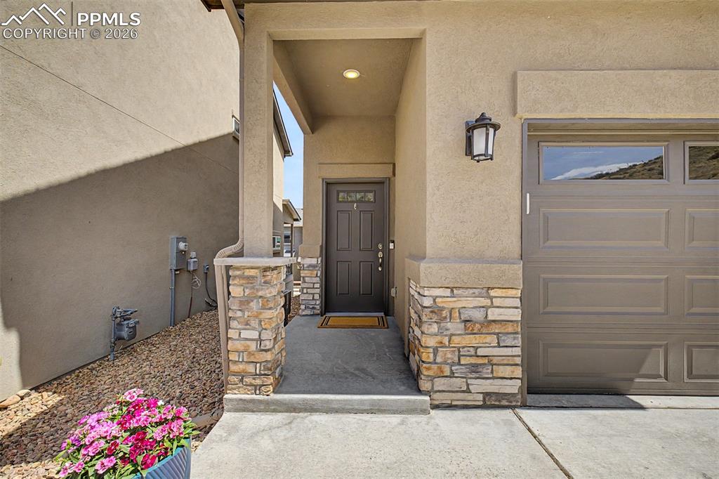 Image 2 of 39: Where stacked stone columns frame a handsome dark front door — the kind of