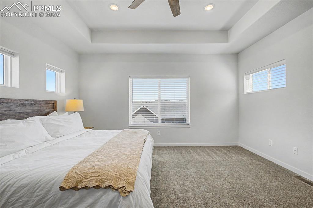 Image 20 of 39: Light pours through multiple windows in the primary suite, keeping the room