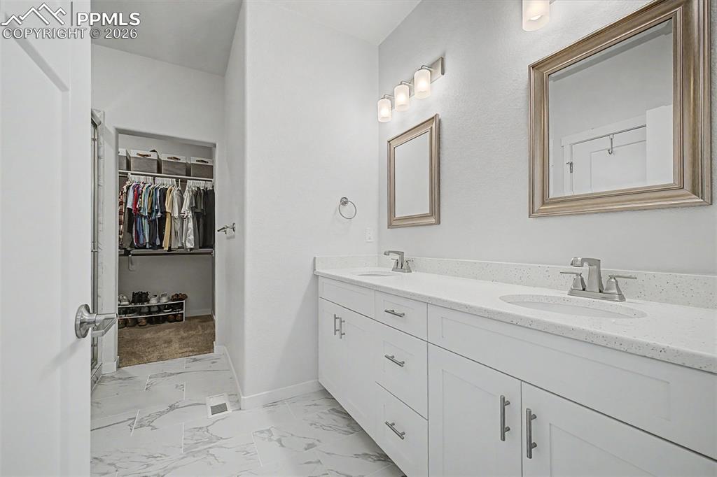 Image 21 of 39: The primary bath leads seamlessly into a spacious walk-in closet, offering