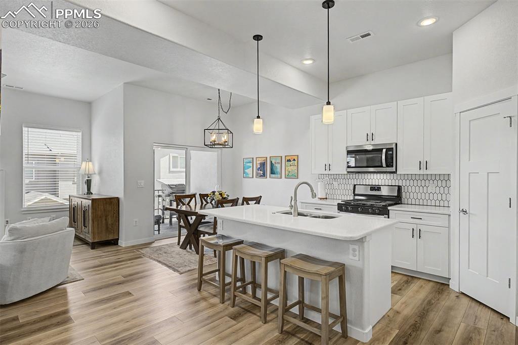 Image 5 of 39: The full rhythm of the kitchen and dining area are complimented with white