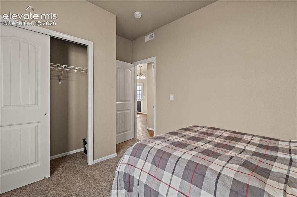 Image 11 of 36: Carpeted room with a sliding closet door, wire shelving, and neutral wall t