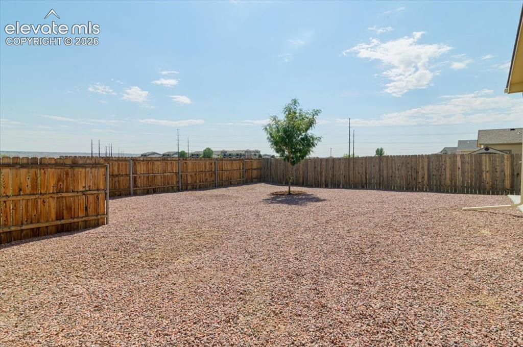 Image 21 of 36: Expansive backyard featuring a full privacy fence and gravel landscaping