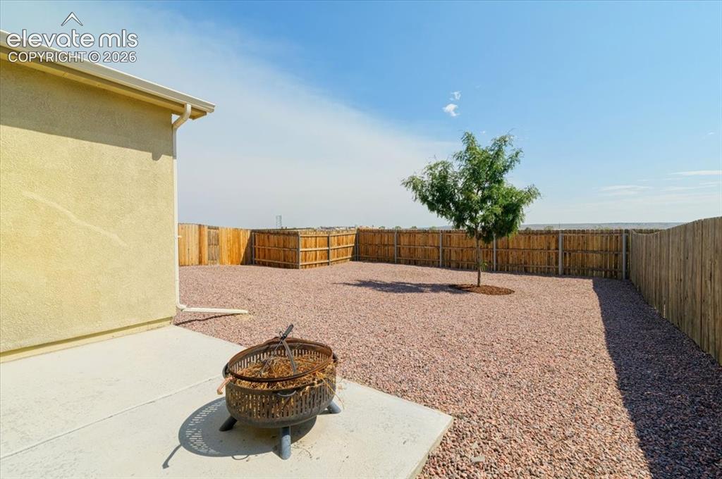 Image 24 of 36: Stucco exterior, concrete patio, gravel hardscaping, privacy fencing, and a