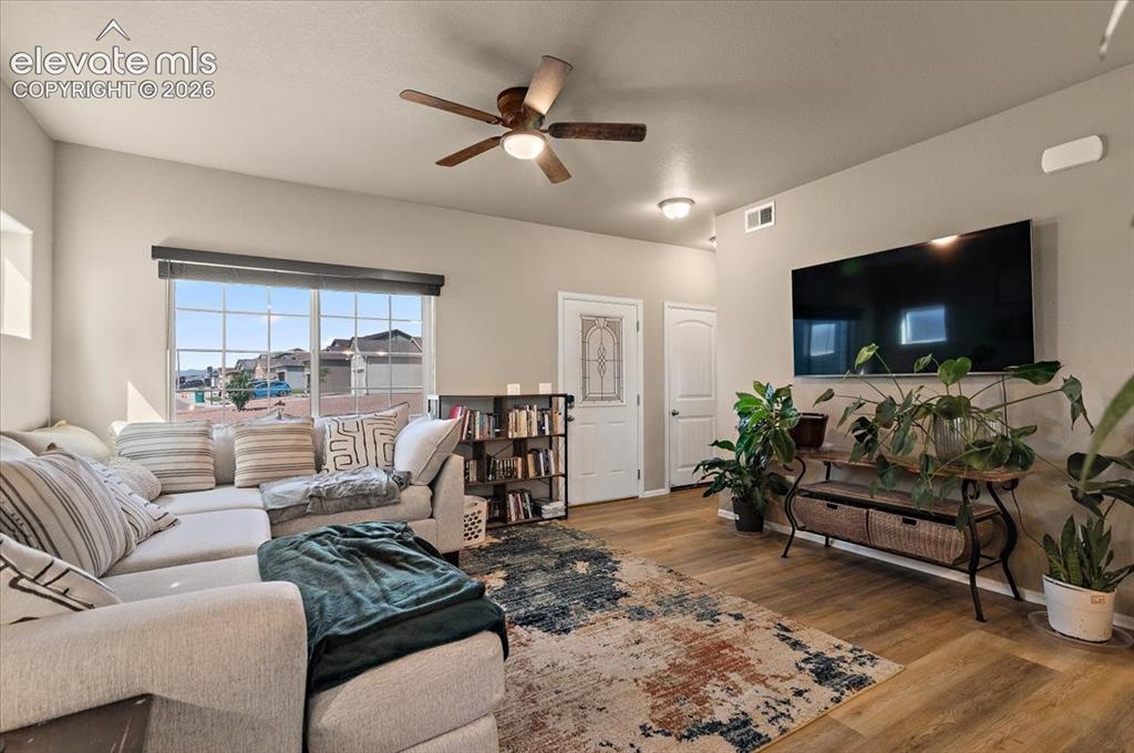 Image 7 of 36: Spacious room featuring wood-finish flooring, a ceiling fan, and large wind