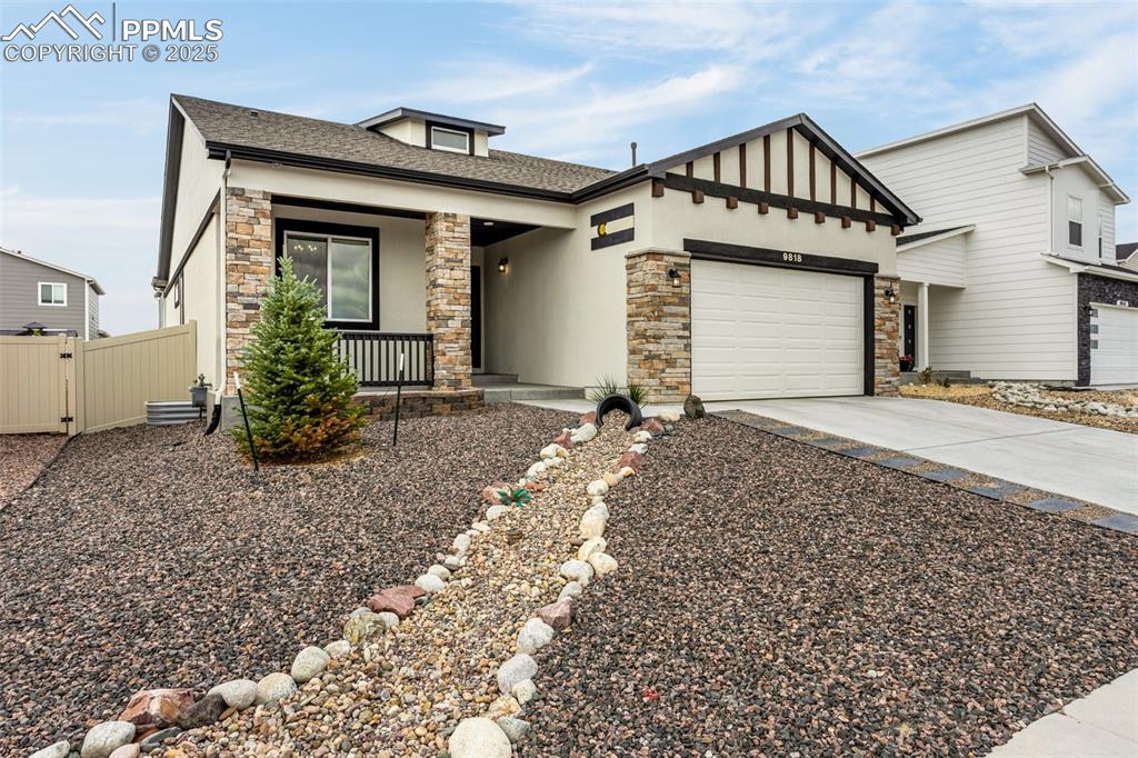 Caption: View of front of property featuring stone siding, a porch, driveway, a shingled roof, and a garage