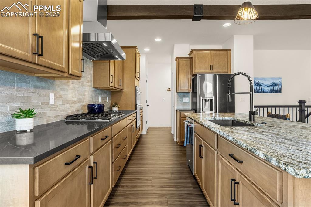 Image 10 of 41: Kitchen with wall chimney range hood, recessed lighting, dark stone counter