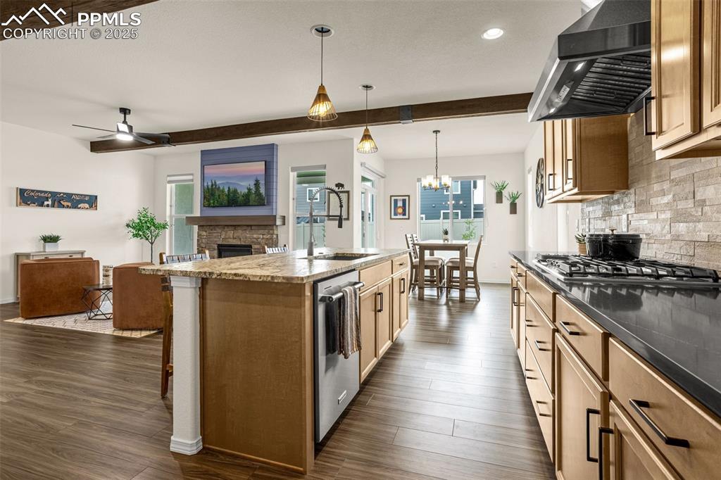 Image 12 of 41: Kitchen featuring a fireplace, wall chimney range hood, a breakfast bar, da