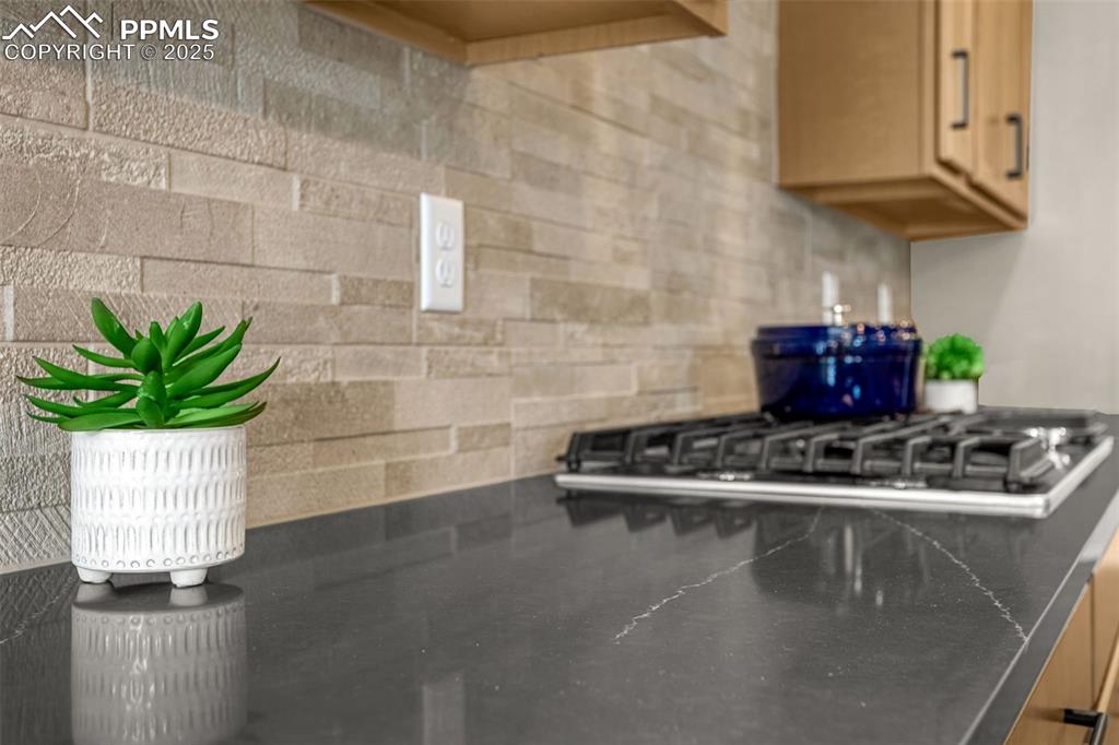 Image 15 of 41: Kitchen featuring stainless steel gas stovetop and dark countertops