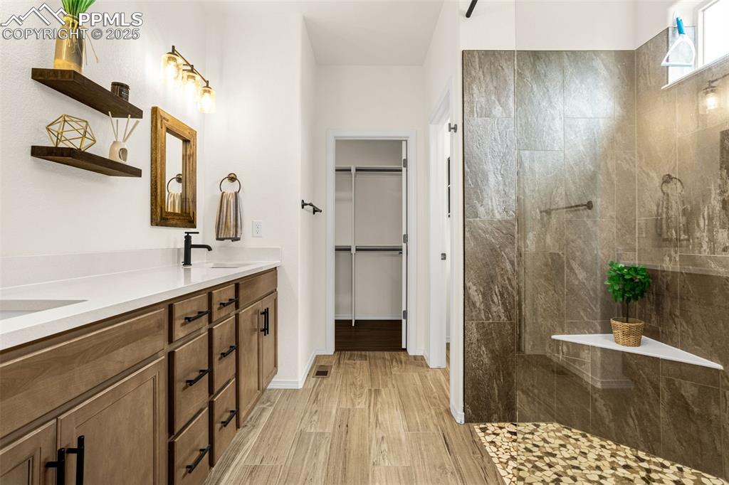 Image 18 of 41: Bathroom with double vanity, wood finished floors, walk in shower, and a wa