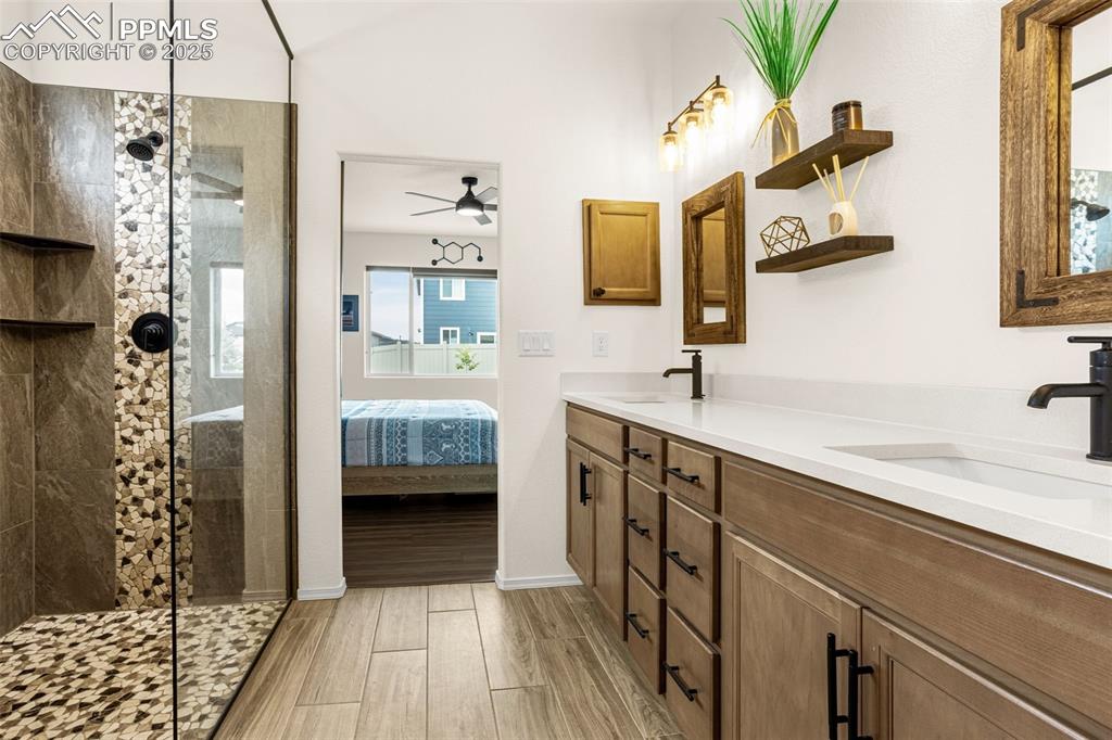 Image 19 of 41: Ensuite bathroom with double vanity, tiled shower, wood finish floors, and 