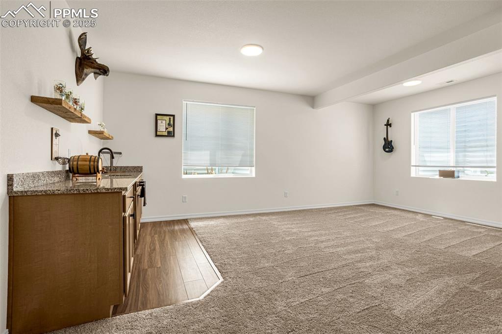 Image 25 of 41: Unfurnished living room featuring carpet floors, wet bar, and wood finished