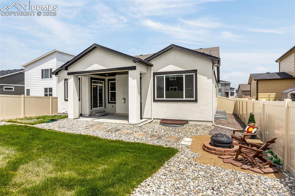 Image 31 of 41: Rear view of property with stucco siding, a fire pit, a fenced backyard, an