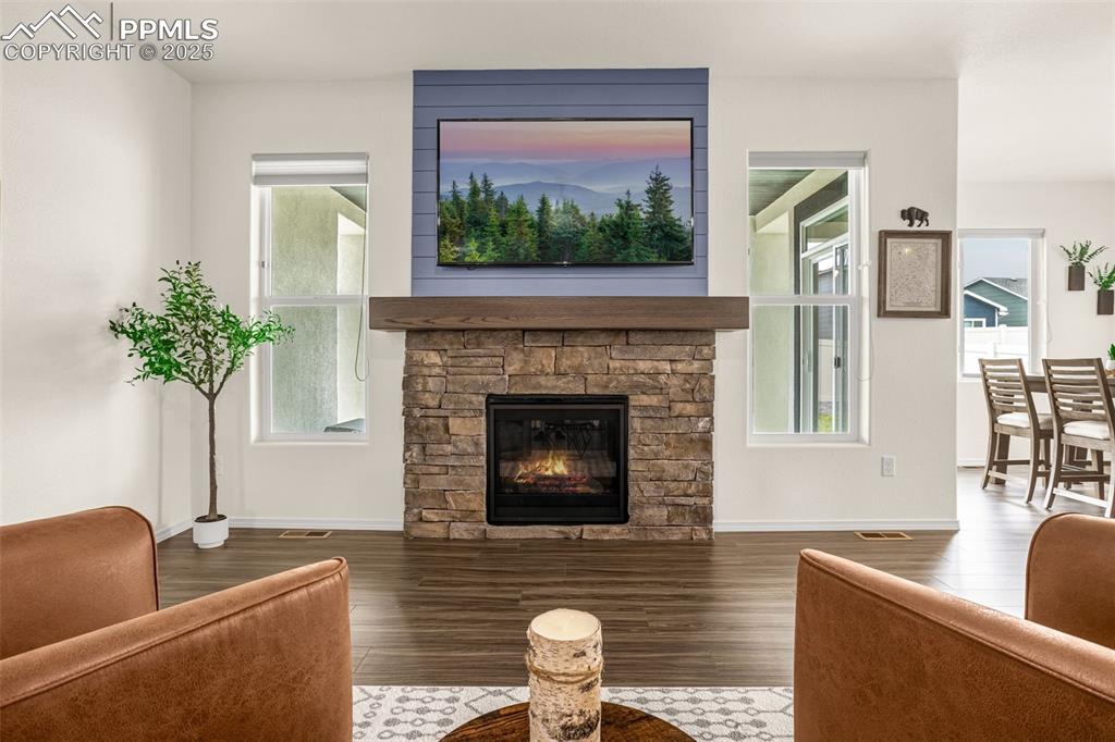 Image 6 of 41: Living area featuring a stone fireplace, plenty of natural light, and wood 