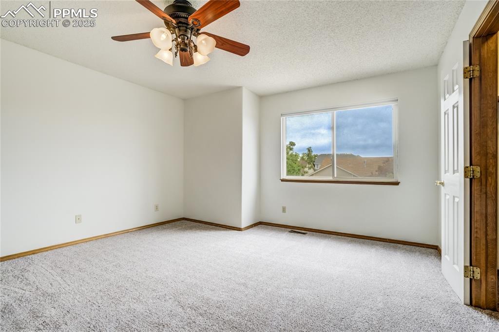 Image 12 of 34: Empty room with carpet, a textured ceiling, and a ceiling fan