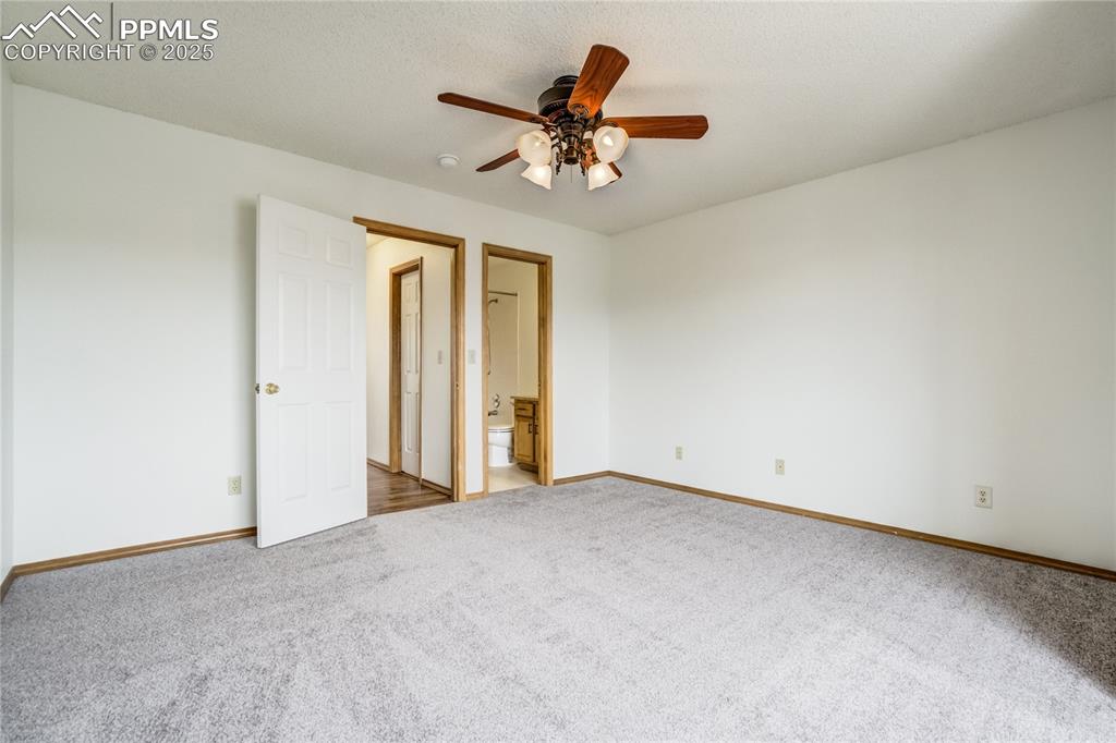 Image 14 of 34: Unfurnished bedroom with carpet floors, ensuite bath, and ceiling fan