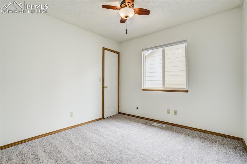 Image 17 of 34: Carpeted empty room with a textured ceiling and ceiling fan
