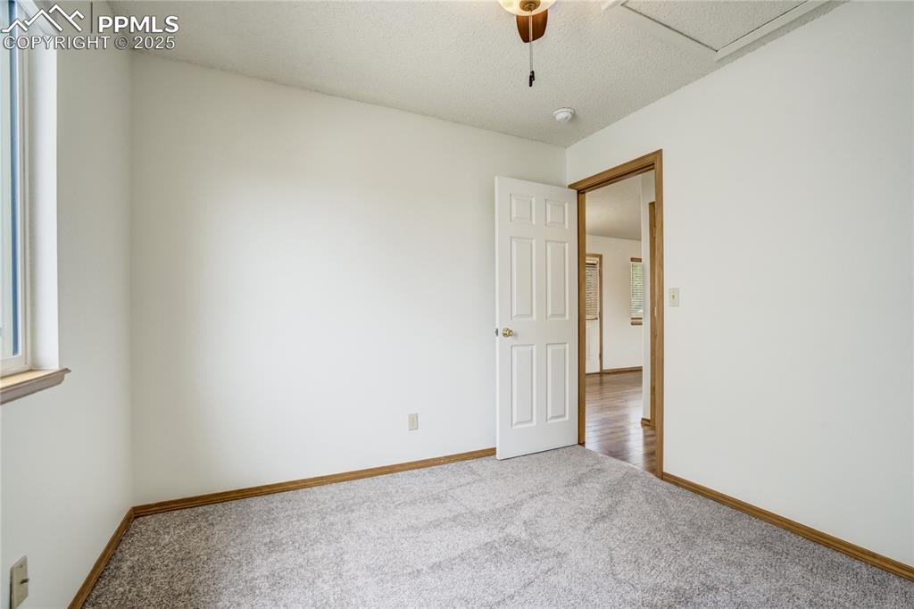Image 18 of 34: Carpeted empty room featuring a textured ceiling and ceiling fan