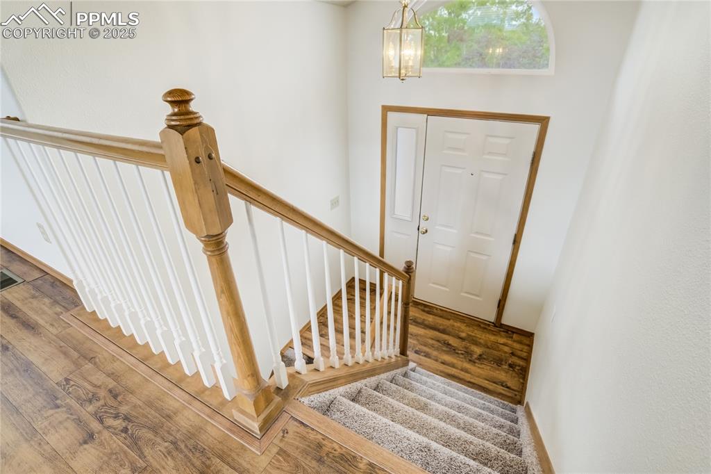 Image 19 of 34: Foyer entrance with stairway, wood finished floors, and a chandelier