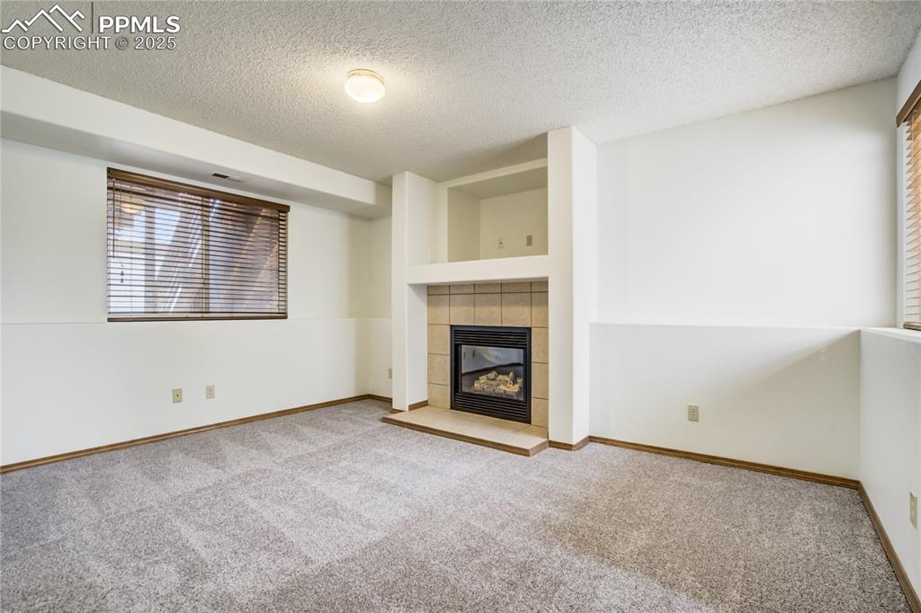 Image 20 of 34: Unfurnished living room featuring a textured ceiling, a tile fireplace, and